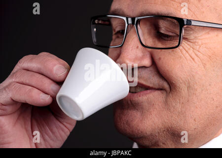 Bald vecchio sorridente imprenditore tenendo una tazza di caffè espresso italiano Foto Stock