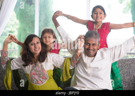 Felice famiglia indiana a casa. Asian i genitori a giocare con i loro bambini seduti sul divano. I genitori e i bambini piscina stile di vita. Foto Stock