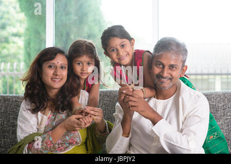 Felice famiglia indiana a casa. Asian genitori con i loro bambini seduti sul divano. I genitori e i bambini piscina stile di vita. Foto Stock