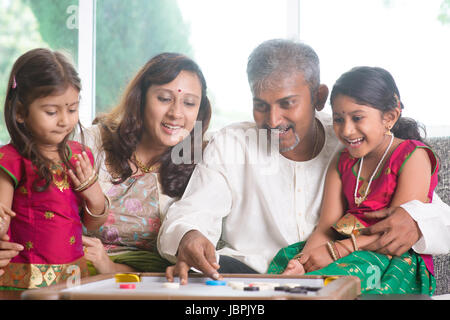 Felice Asian famiglia indiana giocando carrom gioco a casa. I genitori e i bambini piscina stile di vita. Foto Stock