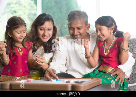 Asian famiglia indiana giocando carrom gioco a casa. I genitori e i bambini piscina stile di vita. Foto Stock