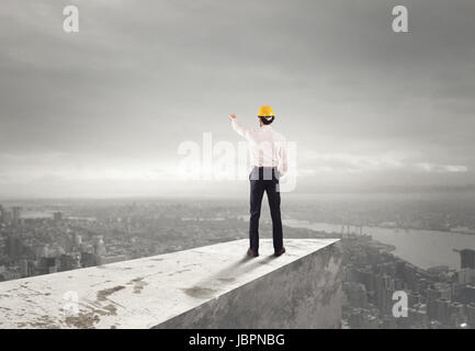 Imprenditore con casco indica la giusta direzione Foto Stock