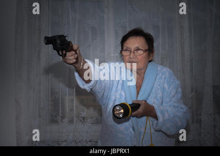 Spaventata senior donna puntando una pistola e torcia. Foto Stock