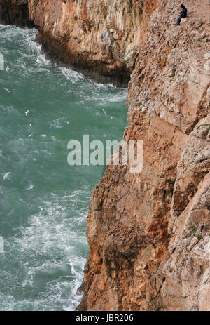 Grave seascape drammatica con il pescatore in Capo San Vicent cliffs, Portogallo Foto Stock