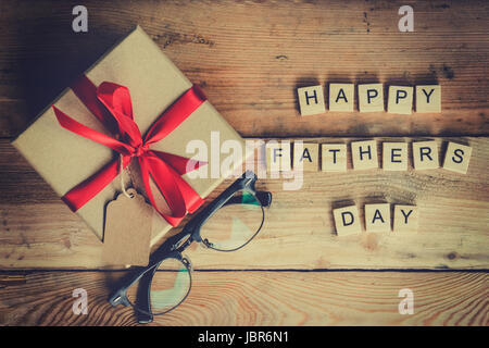 Felice Festa del papà di blocco e confezione regalo con gli occhiali su uno sfondo di legno. Foto Stock