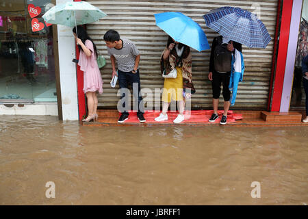 Guiyang, della Cina di Guizhou. 11 Giugno, 2017. Persone in stand by un invaso street in Weining County, a sud-ovest della Cina di Guizhou, 11 giugno 2017. Heavy Rain hit Guizhou dal Domenica. Credito: Egli Huan/Xinhua/Alamy Live News Foto Stock