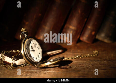 Vintage orologio da tasca su una superficie di legno contro libri antichi Foto Stock