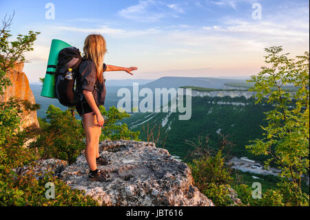 Giovane donna escursioni ai raggi del tramonto, in piedi in cima Tope Kermen, Crimea, Ucraina Foto Stock