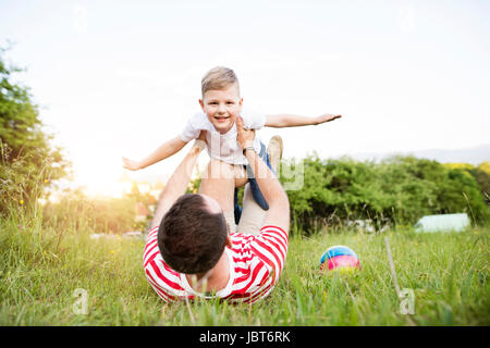 Hipster padre e figlio piccolo sul prato verde. Soleggiata giornata estiva. Foto Stock