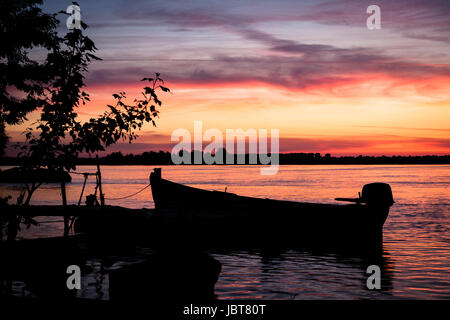 Rosa tramonto. Silhouette di una barca ancorata su un molo nel fiume Danubio, Romania Foto Stock