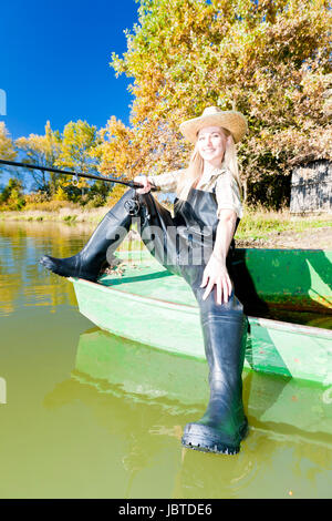 La pesca donna seduta su barca Foto Stock