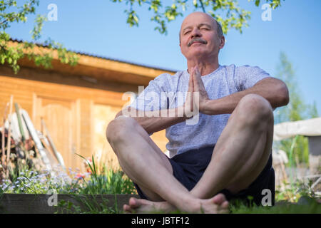 Senior uomo con i baffi con namaste seduta.Concetto di calma e di meditazione. Foto Stock