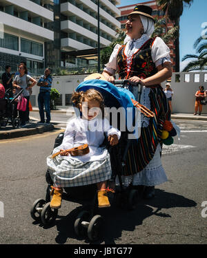 Puerto de la Cruz Tenerife Isole Canarie - 30 Maggio 2017: una bambina vestito in abiti tradizionali si siede in un passeggino e trattiene il canarino guita Foto Stock