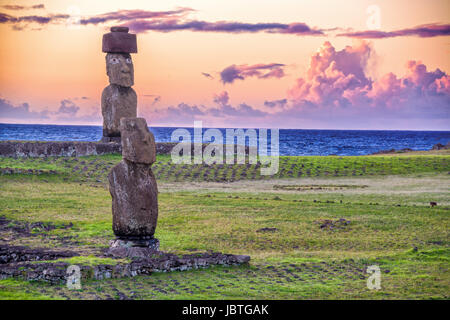 Due statue Moai dell'Isola di Pasqua con un purpureo tramonto dietro di loro Foto Stock