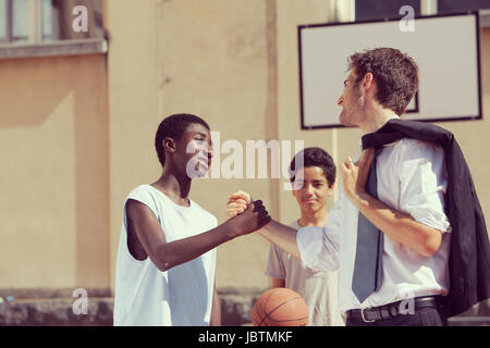 Multi-Ethnic giocatori di basket stringono le mani dopo la partita Foto Stock