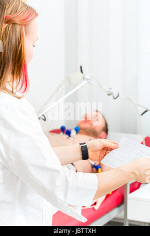 Medico donna analizzando elettrocardiogramma ECG del paziente in ospedale Foto Stock