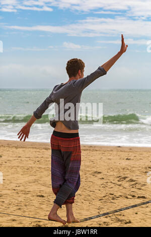 Uomo su gibbon slackline jibline slacklining bilanciamento atto a Bournemouth Beach, Dorset in giugno Foto Stock