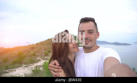 Sorridendo felice coppia tenendo selfie in montagna, antenna. vista città Foto Stock