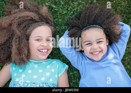 Ritratto di due ragazze, giacente su erba, ridere, vista aerea Foto Stock