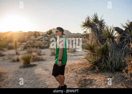 Giovane uomo nel Parco nazionale di Joshua Tree al tramonto, CALIFORNIA, STATI UNITI D'AMERICA Foto Stock