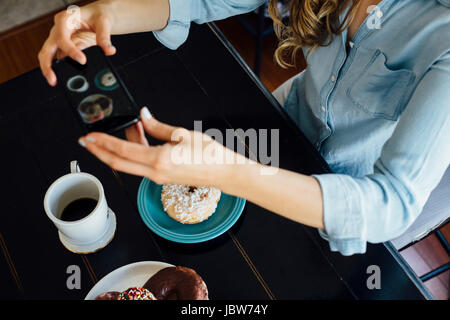 Vista aerea della donna a fotografare il foro della ciambella e del caffè sulla tabella Foto Stock