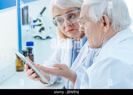 Coppia senior di scienziati lavora con tavoletta digitale in laboratorio Foto Stock