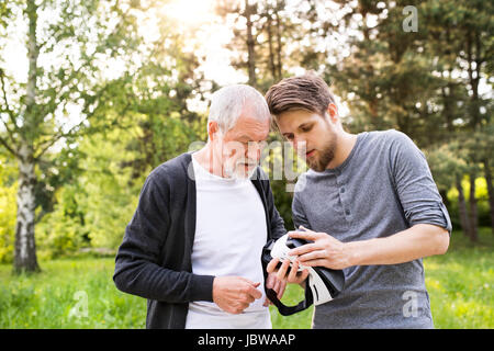 Il giovane e il suo anziano padre con occhiali VR all'esterno. Foto Stock