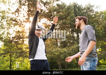 Il giovane e il suo anziano padre con occhiali VR all'esterno. Foto Stock