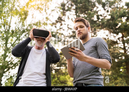 Il giovane e il suo anziano padre con occhiali VR all'esterno. Foto Stock