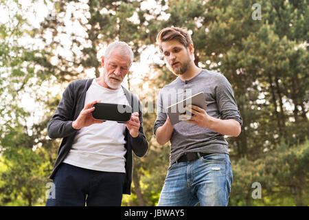 Il giovane e il suo anziano padre con occhiali VR all'esterno. Foto Stock