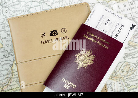 Concetto di viaggio con un diario di viaggio con logo di aereo, fotocamera e bussola, accompagnato da un passaporto francese, carta d'imbarco e una mappa vintage Foto Stock