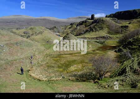 Due persone che camminano vicino alla torre rocciosa del castello di Ewen & la conformata a cono collinette in Fairy Glen vicino a Uig, Isola di Skye,North West Highlands scozzesi, Foto Stock