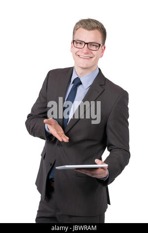 Freigestelltes Foto eines jungen, lächelnden Geschäftsmannes, der ein Tablet präsentiert. Der Mann schaut zur Kamera. Foto Stock