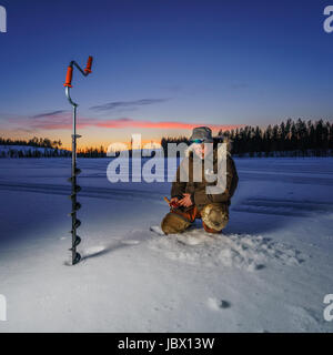 Pesca sul ghiaccio, Kangos, Lapponia, Svezia Foto Stock