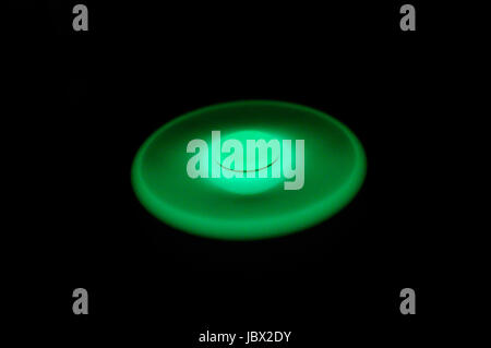 Incandescente verde nel buio agitano: spinner la filatura su sfondo nero Foto Stock