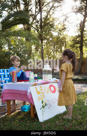 Ragazza di acquisto da limonata lemonade stand in giardino Foto Stock