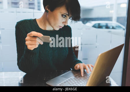 Donna in cafe effettuare il pagamento con carta di credito sul computer portatile Foto Stock