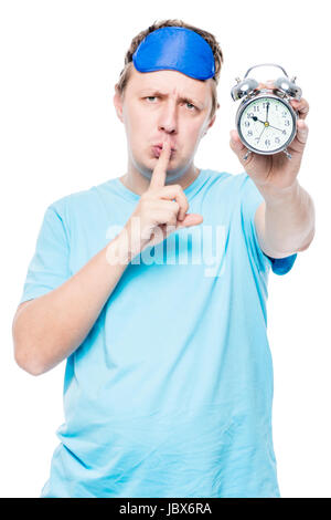 Ritratto verticale di un uomo con un orologio di allarme mostra un gesto di un dito vicino le labbra, afferma che è necessario essere silenziosi Foto Stock