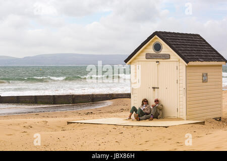 Coppia matura seduta dalla Capanna Di Nozze a Bournemouth Beach a Bournemouth Dorset in giugno Foto Stock