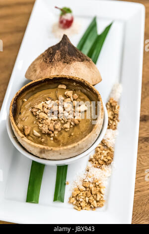 Crema di noce di cocco servita nel suo guscio Foto Stock