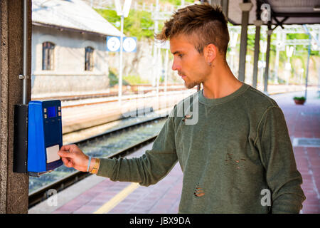 Giovane uomo mettendo card ticket a macchina sulla stazione. Foto Stock
