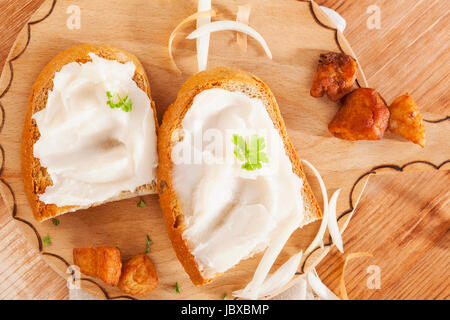 Deliziose le fette di pane con lardo e scratchings su vintage tagliere di legno vista dall'alto. Culinaria pane tradizionale paese europeo style mangiare. Foto Stock