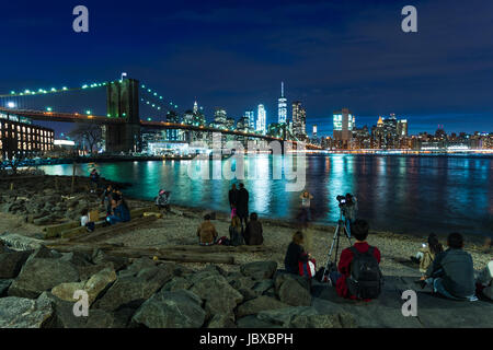 Le persone che si godono la vista da DUMBO verso Manhattan con il ponte di Brooklyn, New York Foto Stock