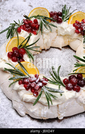 Pavlova torta a forma di una ghirlanda di Natale di meringa con panna, melograno, cranberry, rametti di rosmarino Foto Stock