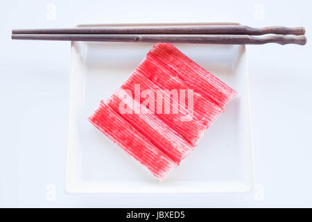 Set di bastoncini di granchio con bacchette di legno sulla piastra bianca, stock photo Foto Stock