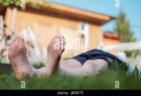 Uomo che stabilisce il campo d'erba. Egli relax nella natura in estate. Cercare su sky Foto Stock