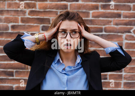 Frustrati business donna tiene le mani alla sua testa in frustrazione Foto Stock