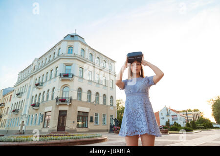 Giovane donna in abiti estivi con dispositivo di VR per esterno Foto Stock