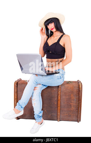 Junge Frau sitzt mit Laptop auf altem Koffer Foto Stock