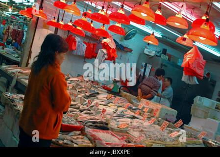 Ritratto orizzontale di un locale donna cinese acquisto di pesce fresco al mercato umido a Wan Chai, Hong Kong. Foto Stock